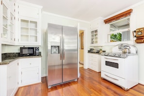 A kitchen with white cabinets, a stainless steel refrigerator, a microwave, and a white stove.
