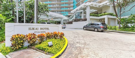 The Ilikai Hotel entrance with a sign, a covered walkway, and a parking area.