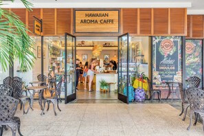 A cafe with a wooden facade and a sign reading "HAWAIIAN AROMA CAFFE". - Ilikai Hotel Condo With Ocean, Lagoon & Fireworks Views (Honolulu)