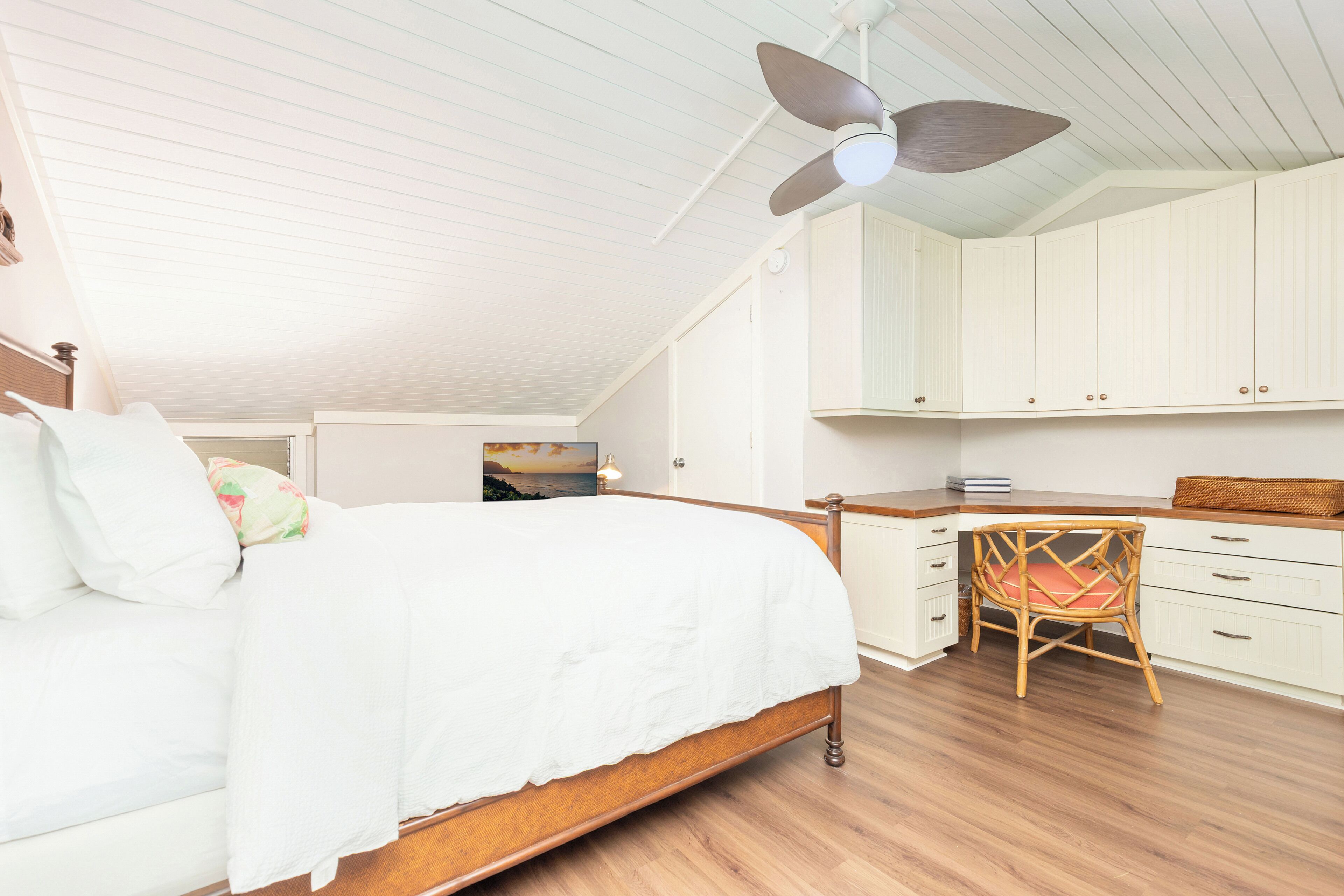 A bedroom with a bed, a chair, a desk, and a ceiling fan.