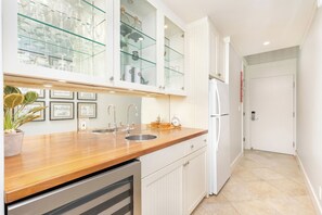 Uma cozinha moderna com bancada de madeira, pia de aço inoxidável e armários brancos.