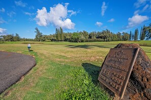 Campo de golfe com uma placa a indicar os números dos buracos e uma chapa com texto.