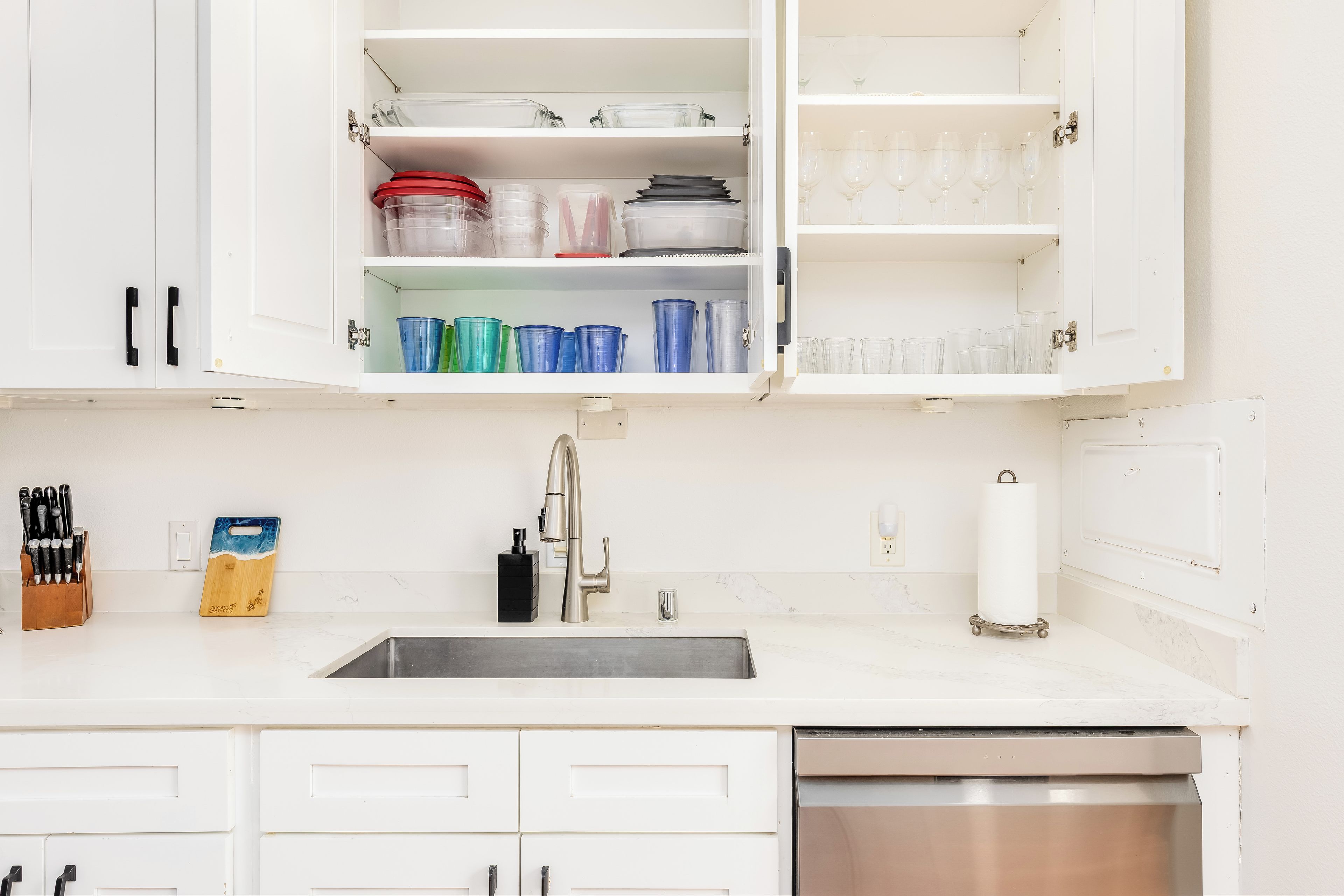 A kitchen with white cabinets, a stainless steel sink, and a dishwasher.
