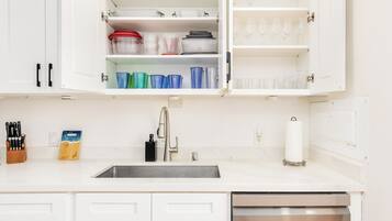 A kitchen with white cabinets, a stainless steel sink, and a dishwasher.