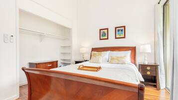 A neatly arranged bedroom with a wooden bed, bedside tables, a nightstand, and a wardrobe.