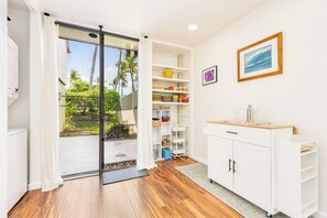 Cozinha moderna com armários brancos, bancada de madeira e vista para o exterior.