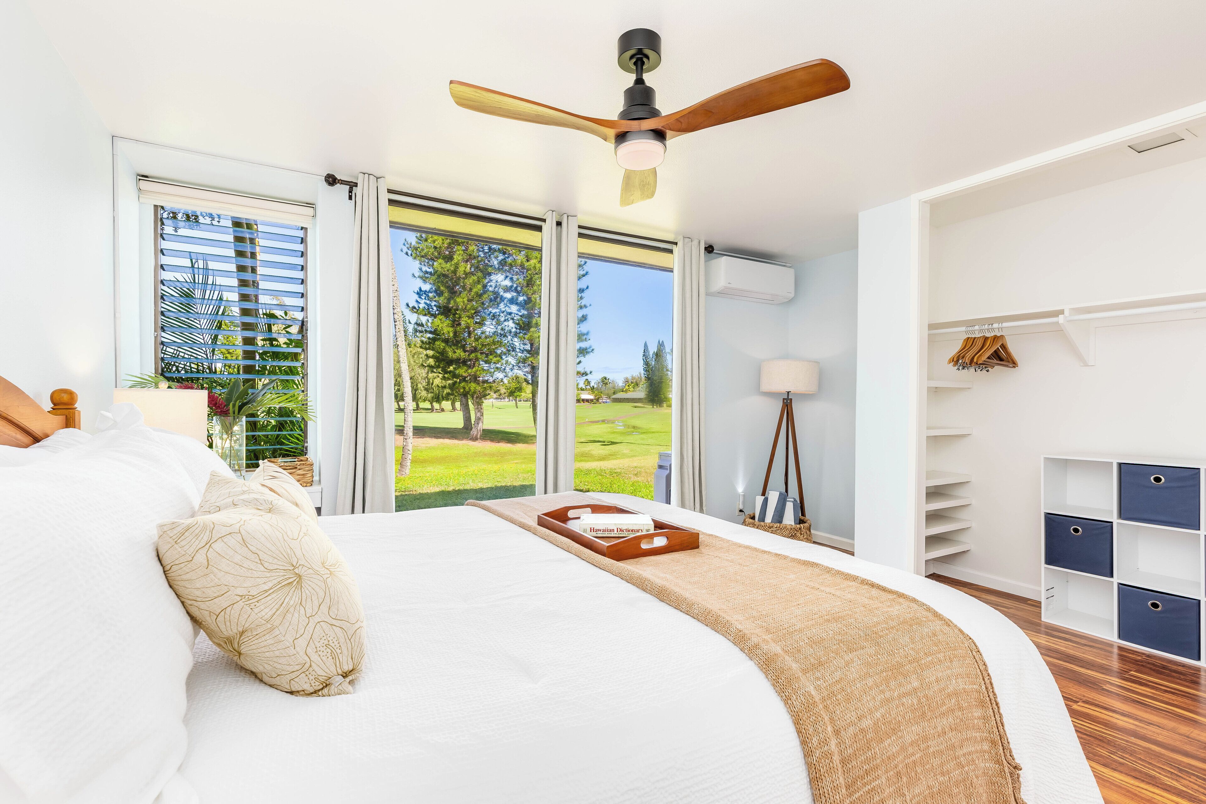 Une chambre avec un grand lit, un ventilateur de plafond et une vue sur un terrain de golf par les fenêtres.