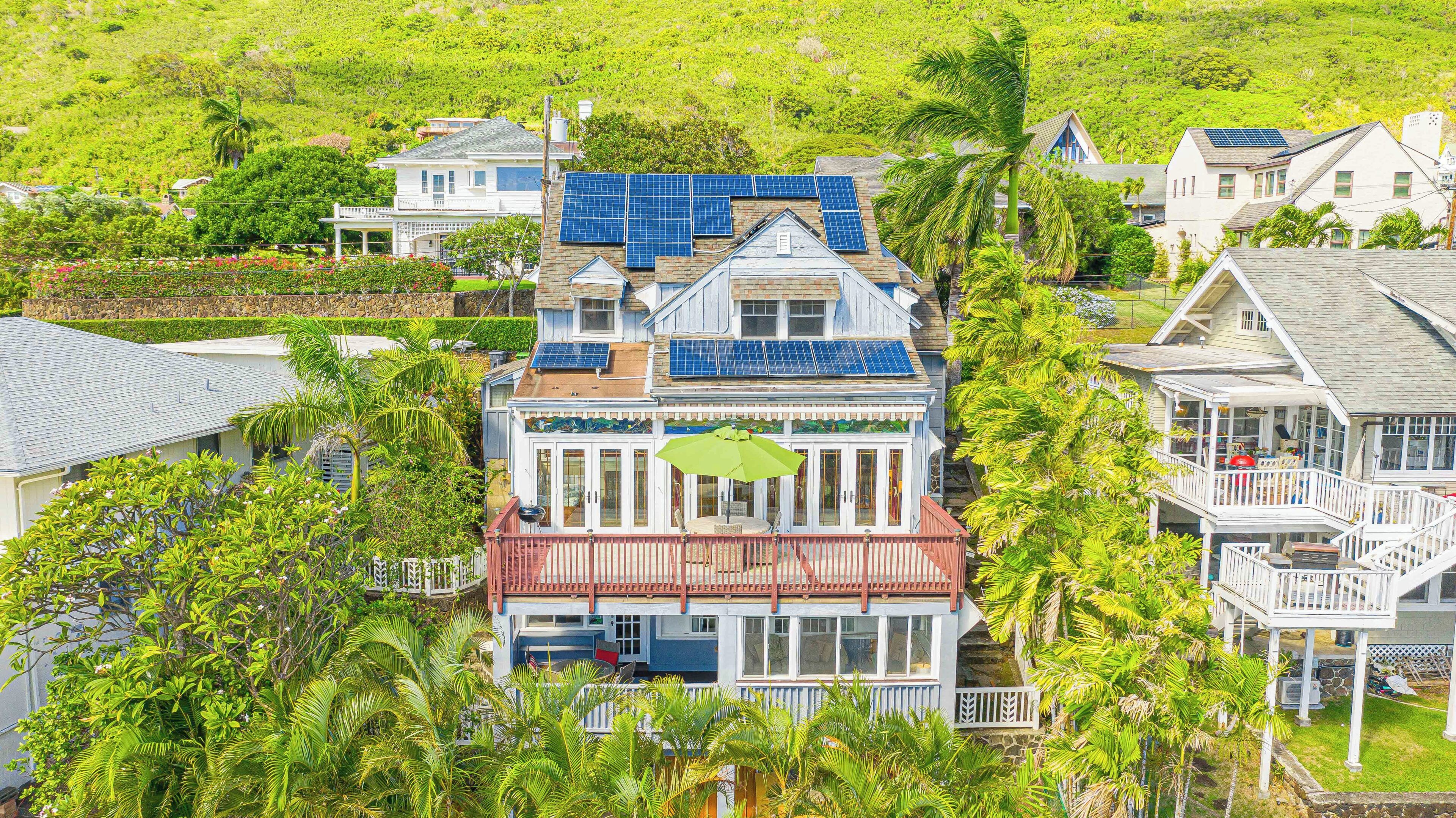 A coastal house with solar panels, a covered patio, and a lush garden.