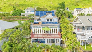 A coastal house with solar panels, a covered patio, and a lush garden.