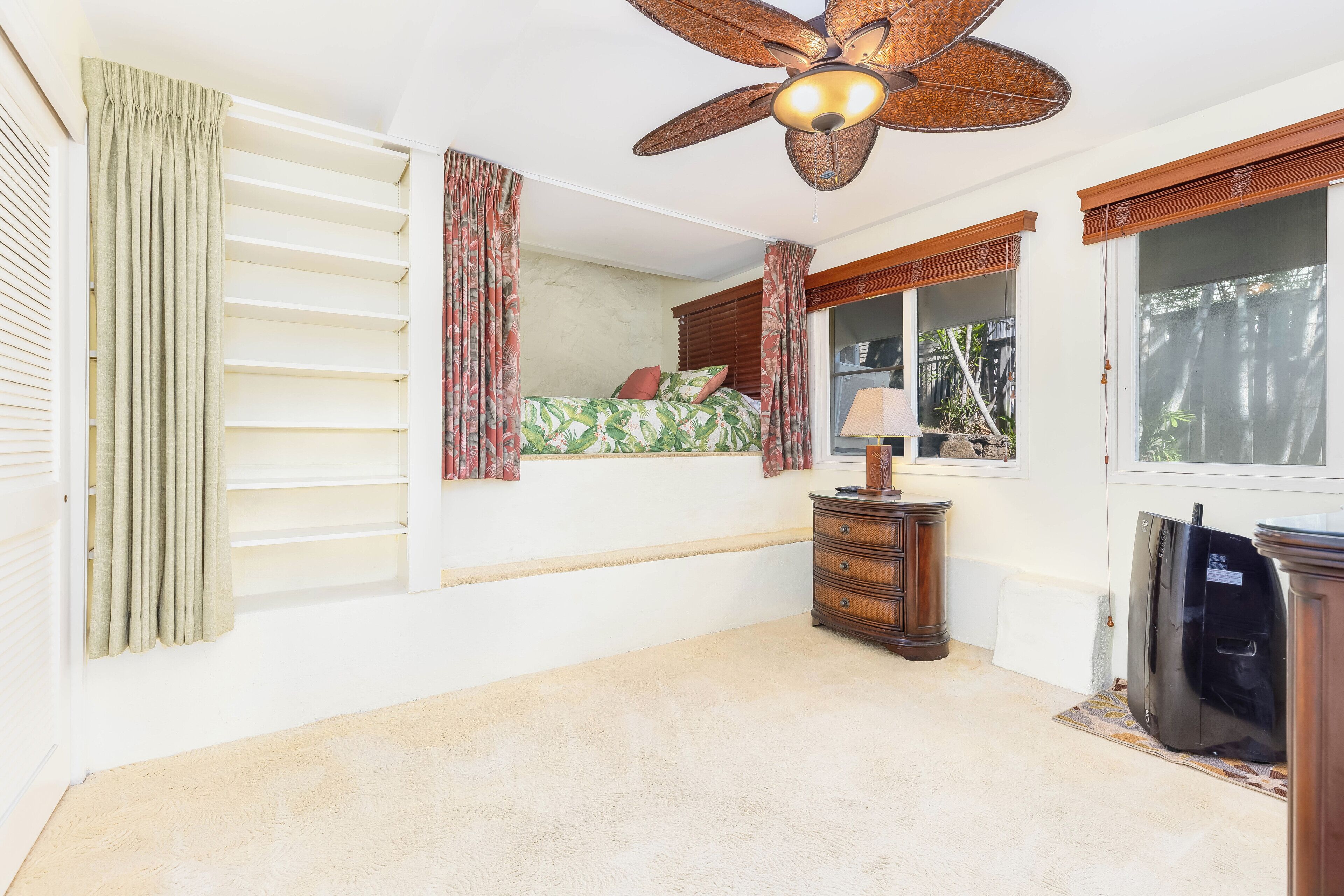 A bedroom with a bed, a ceiling fan, a dresser, and a window.