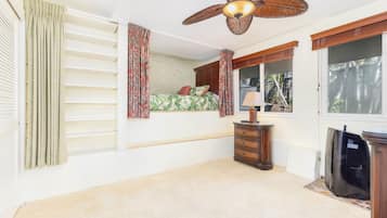 A bedroom with a bed, a ceiling fan, a dresser, and a window.