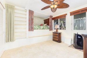 A bedroom with a bed, a ceiling fan, a dresser, and a window.