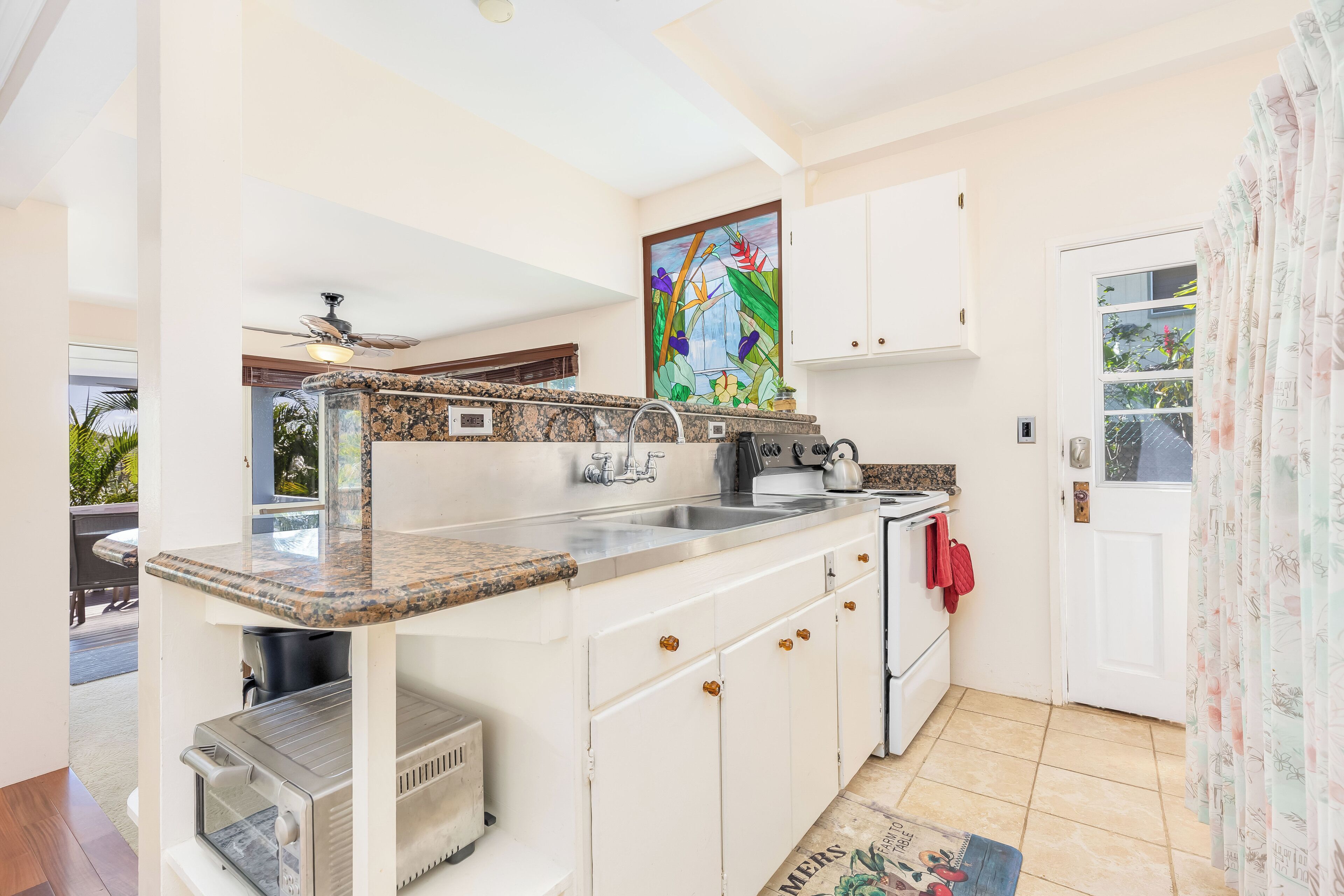 A compact kitchen with white cabinets, a granite countertop, and a built-in oven.