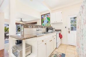 A compact kitchen with white cabinets, a granite countertop, and a built-in oven.