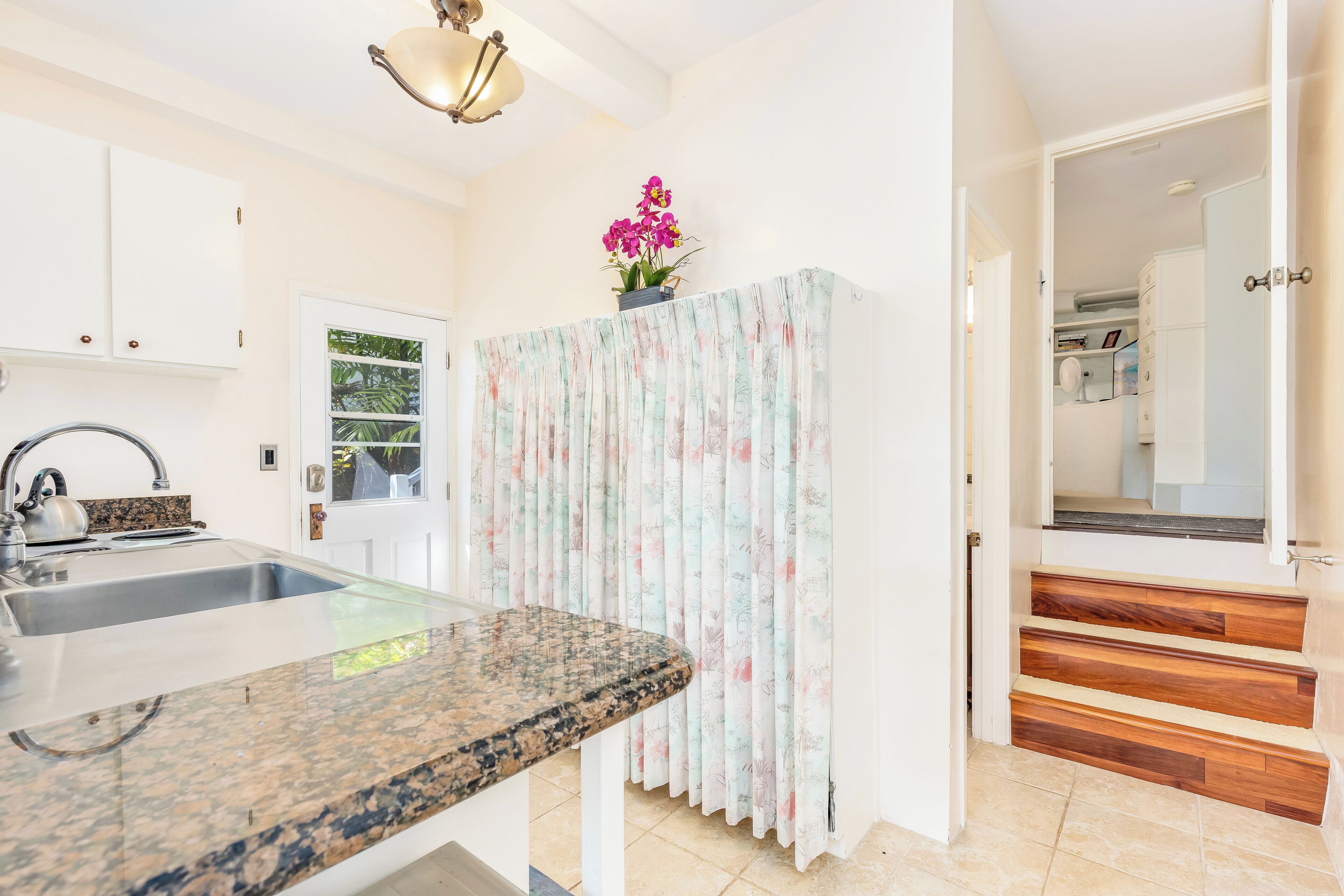 Eine Küche mit einer Arbeitsplatte aus Granit, einem Spülbecken und einem Fenster mit Blick auf Grünflächen.
