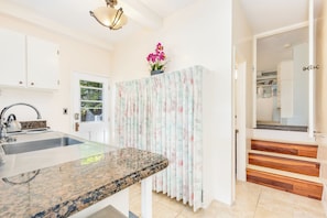 A kitchen with a granite countertop, a sink, and a window with a view of greenery.