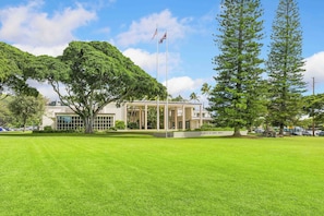 A university campus with a large lawn, a building with a sign reading "University of Hawaii", and two flagpoles with flags.