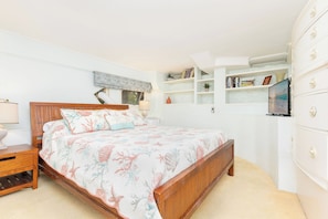 A bedroom with a wooden bed, a nightstand, a dresser, and a shelf with books and decorative items.