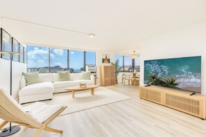Ein modernes Wohnzimmer mit einem weißen Sofa, einem Holztisch und einem großen Flachbildfernseher.
