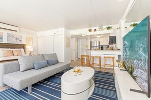 A modern living room with a grey sofa, a white coffee table, and a blue striped rug. - Stunning Ocean & Fireworks Lagoon View From Condo at Ilikai W/full Kitchen (Honolulu)