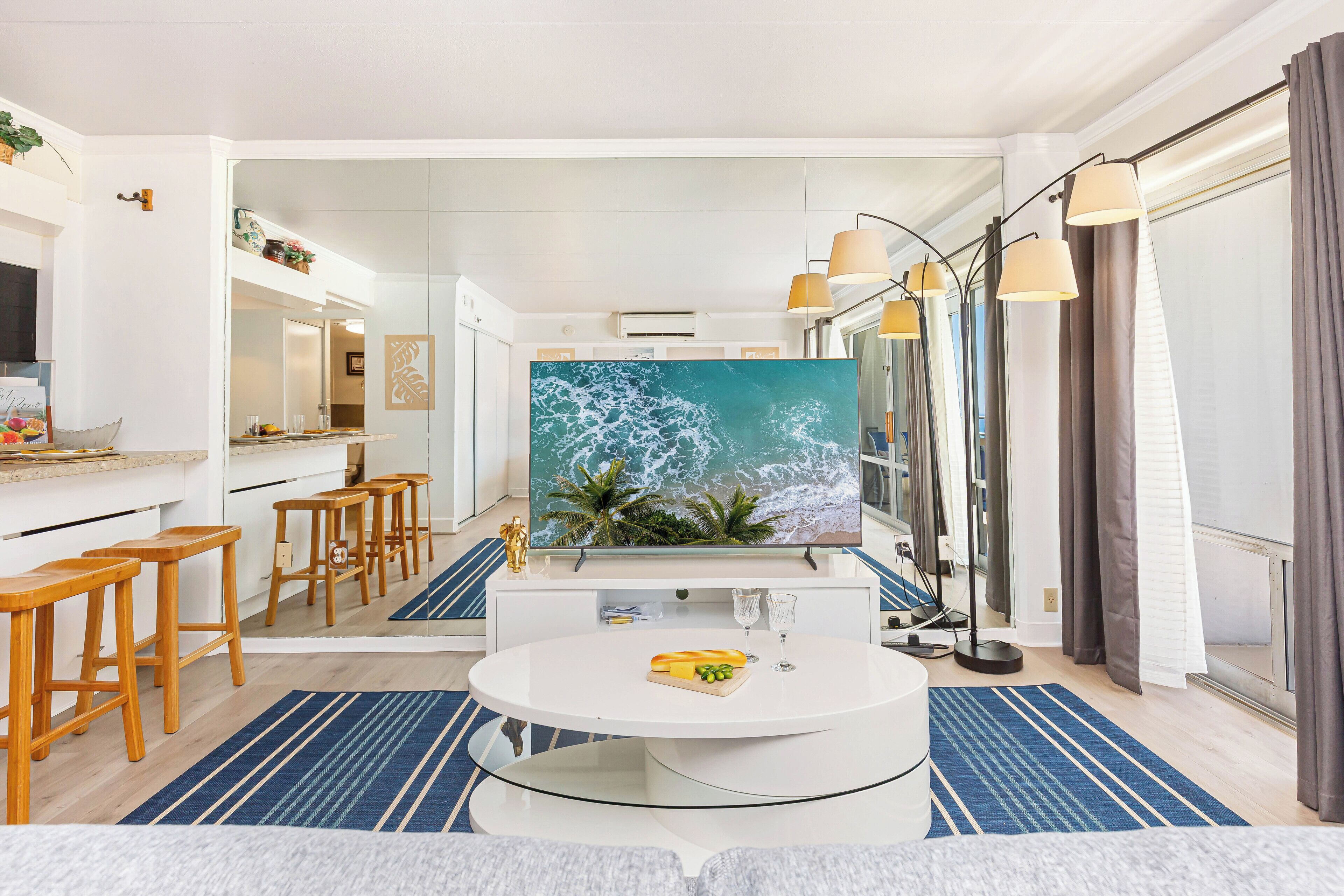 Una cocina moderna con una isla grande, taburetes de madera y una pantalla de televisión grande.