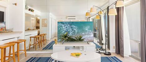 Una cocina moderna con una isla grande, taburetes de madera y una pantalla de televisión grande.