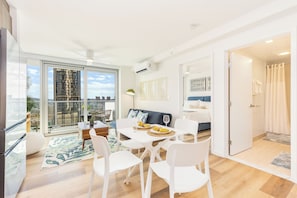 A modern apartment with a dining area, a sofa, and a view of the city. - Modern Stay at The Park on Keeaumoku W/city Views & Luxury Amenities (Honolulu)