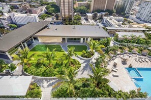 An aerial view of a hotel with a swimming pool, palm trees, and a well-maintained lawn. - Modern Stay at The Park on Keeaumoku W/city Views & Luxury Amenities (Honolulu)