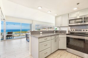 A modern kitchen with a large island, stainless steel appliances, and a view of the ocean. - Ocean-sunset Views Condo Steps Away From the Beach W/awesome Ilikai Amenities (Honolulu)