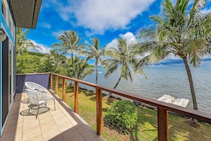 A balcony with a view of the sea, palm trees, and a wooden railing. - Oceanfront Gem in the Beautiful Kaneohe Dream Home Paradise Family Retreat (Kaneohe)