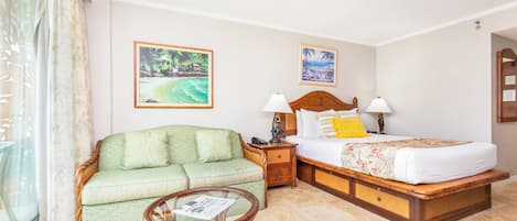 Una habitación de hotel con una cama, un sofá, una mesita y dos cuadros colgados en la pared.