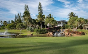 A golf course with a pond, palm trees, and a building with a balcony. - Beach Villas Oceanfront Resort at Ko Olina W/unobstructed Views (Kapolei)