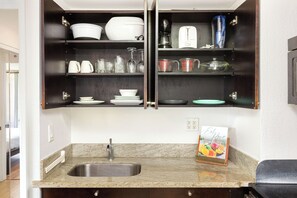 A kitchen with a granite countertop, stainless steel sink, and dark wooden cabinets. - Diamond Head & Golf Course Views at Island Colony W/amazing Amenities (Honolulu)