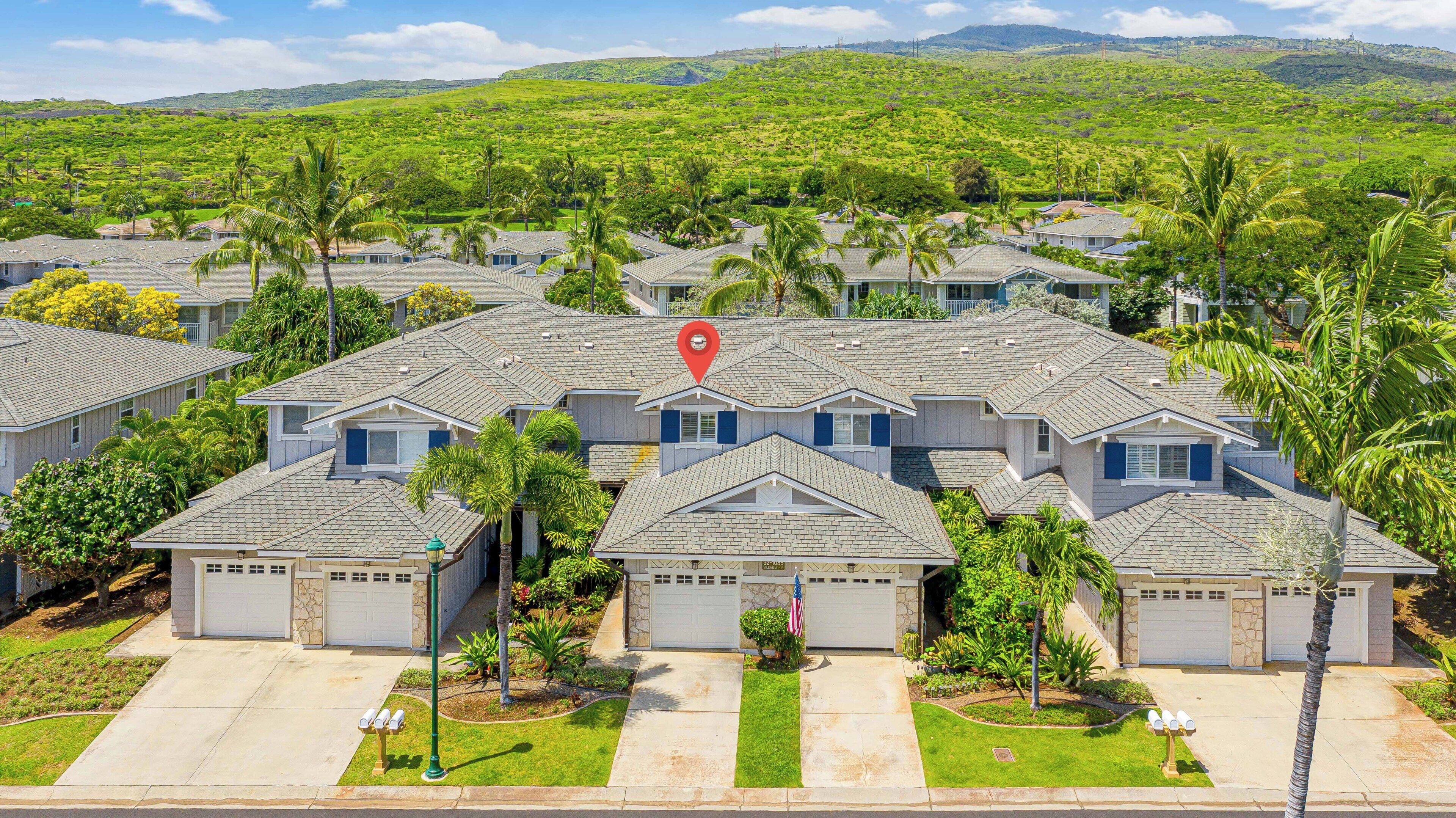 Zona residencial con varias casas, cada una con garaje, rodeada de vegetación y palmeras.
