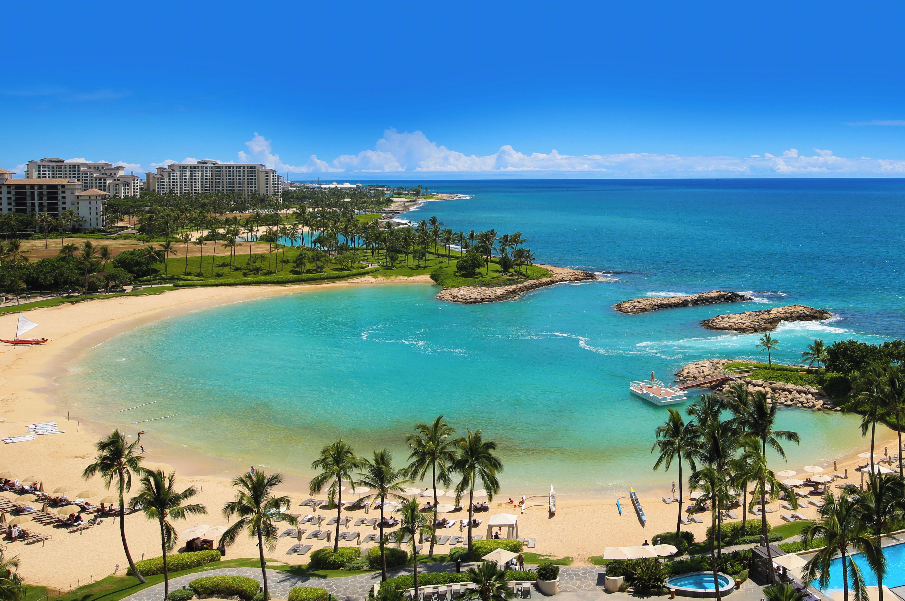 Un resort con playa, aguas turquesas cristalinas y palmeras.