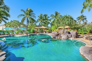 Una piscina cristalina rodeada de palmeras y sillas de descanso.