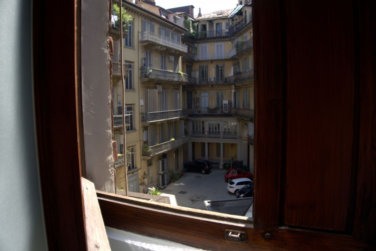A view of a courtyard with multi-story buildings, a wooden railing, and parked cars.