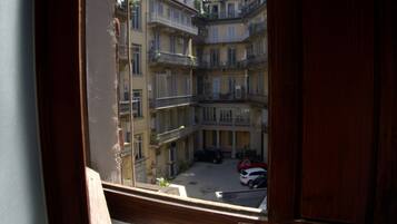 A view of a courtyard with multi-story buildings, a wooden railing, and parked cars.