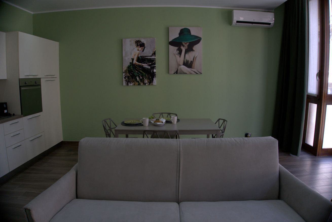 Un soggiorno con un divano, un tavolo da pranzo con sedie e due quadri appesi al muro.