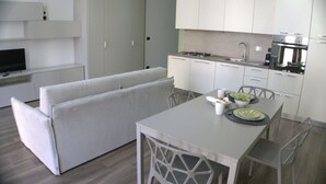 A modern kitchen with white cabinets, a dining table, and a built-in TV. - Solferino Light & Space | Central Turin (Torino)