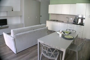 Una cucina moderna con mobili bianchi, un tavolo da pranzo e una TV integrata.