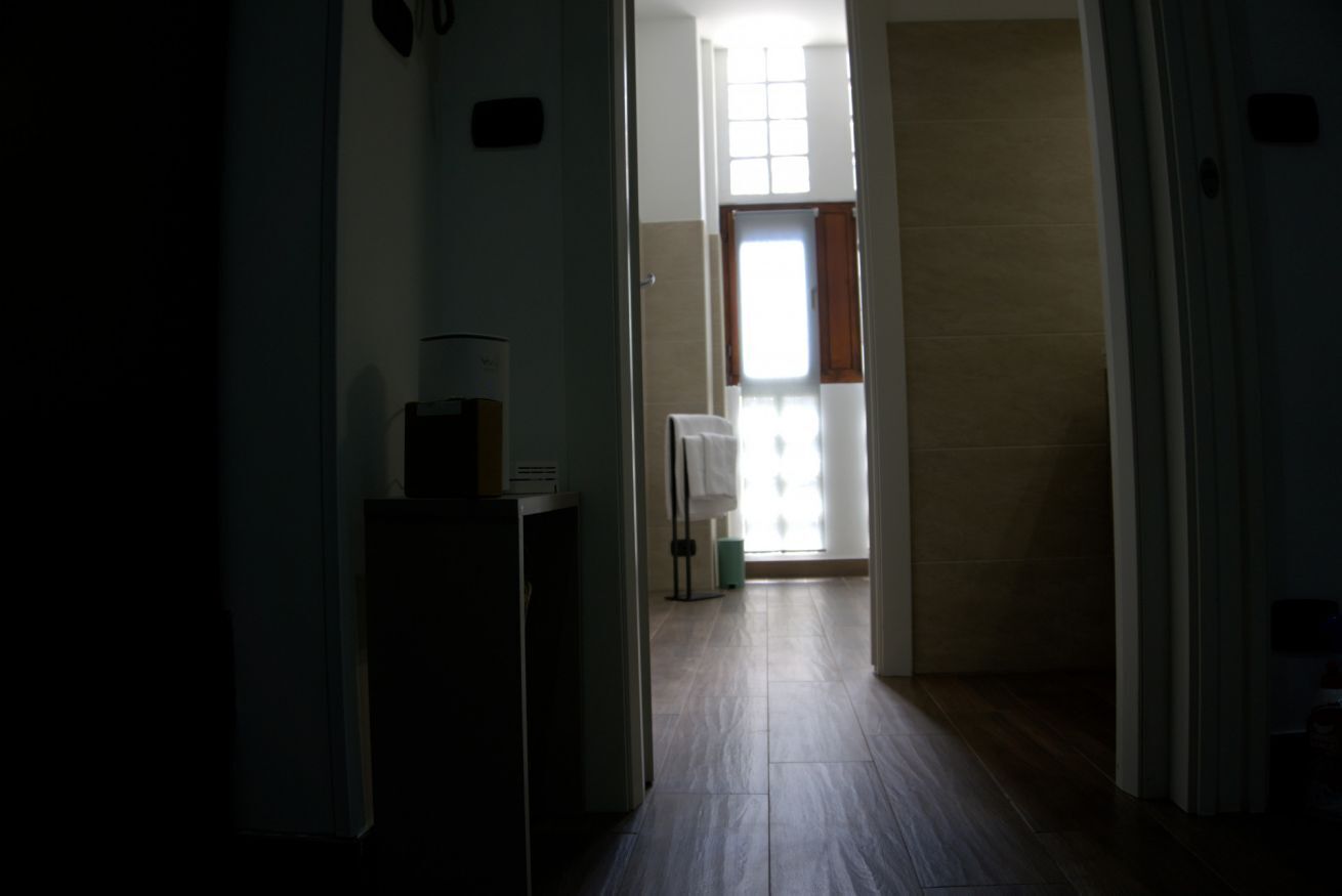 Corridoio che conduce a un bagno con portasci e una finestra con tende.