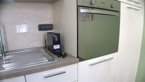 A kitchen with a built-in oven, a coffee machine, and a stainless steel sink. - Solferino Light & Space | Central Turin (Torino)