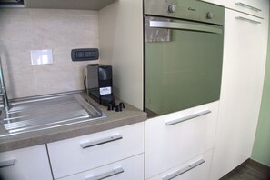 Una cucina con forno integrato, macchina del caffè e lavello in acciaio inossidabile.