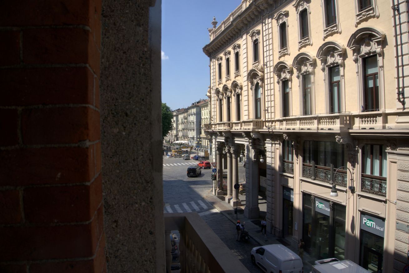 Una vista di strada con un edificio in stile classico, caratterizzato da colonne e cornici di finestre elaborate.