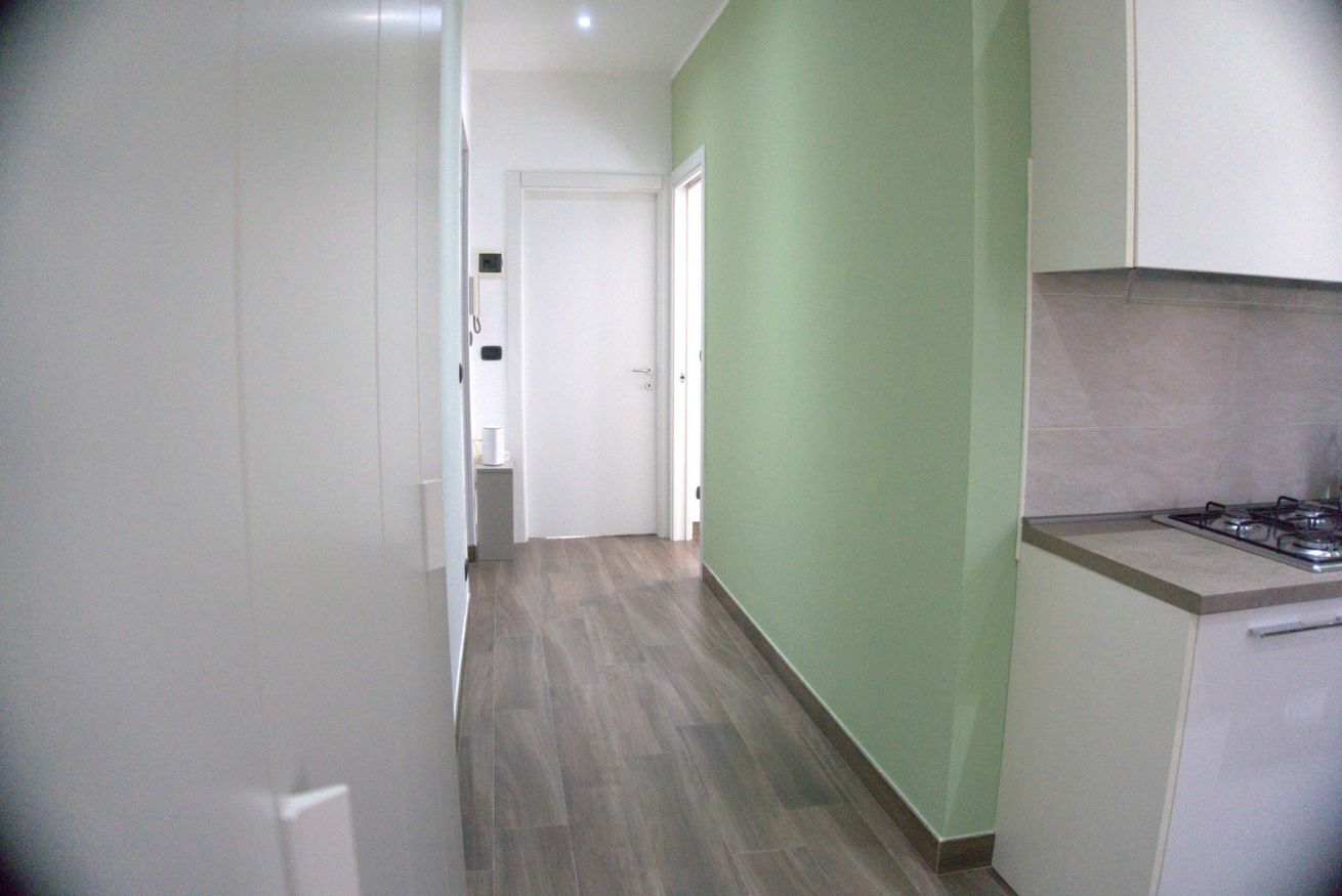 A narrow hallway with a kitchen area on the right, featuring a gas stove and cabinets.
