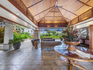 A spacious lobby with a high ceiling, large potted plants, and a view of the surrounding greenery.