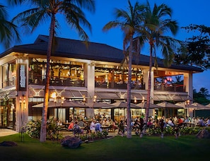 A two-story building with outdoor seating and palm trees.