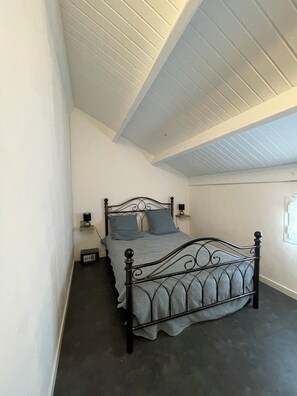 Une chambre avec un lit simple, une table de chevet, une lampe et une petite table avec une autre lampe.