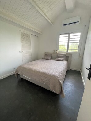 A bedroom with a bed, a window, a radiator, and a door. - House with a pool (Sainte-Anne)